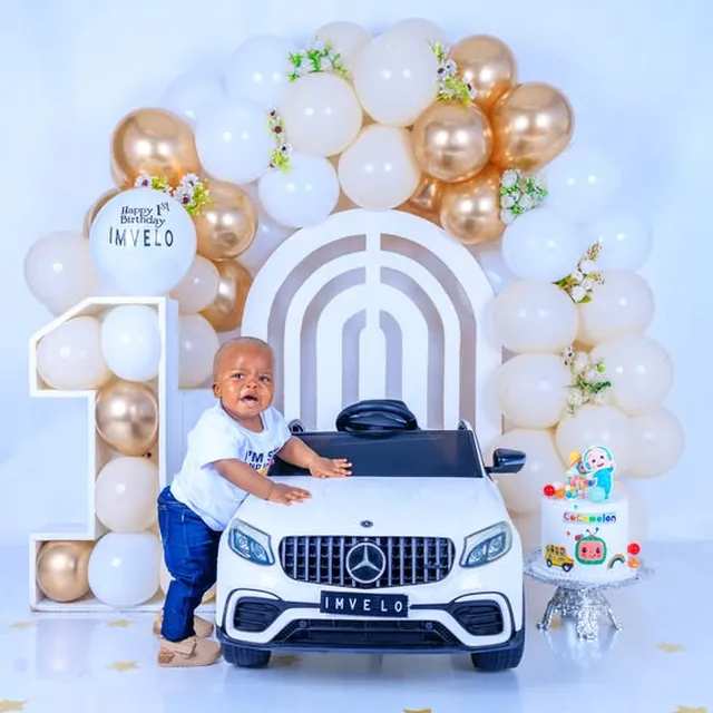 First birthday session, toy Mercedes ride-on, white and gold balloons